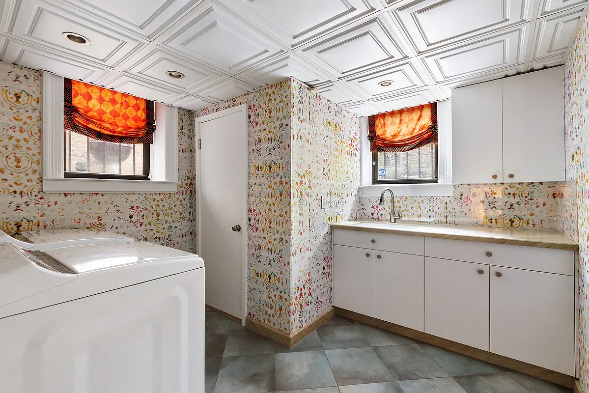 laundry room with batik wallpaper, white cabinets