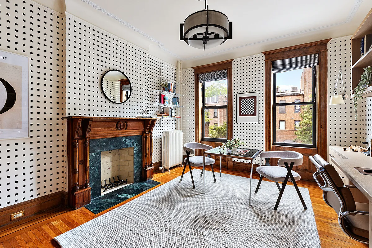bedroom with mantel and black checked wallpaper set up as an office