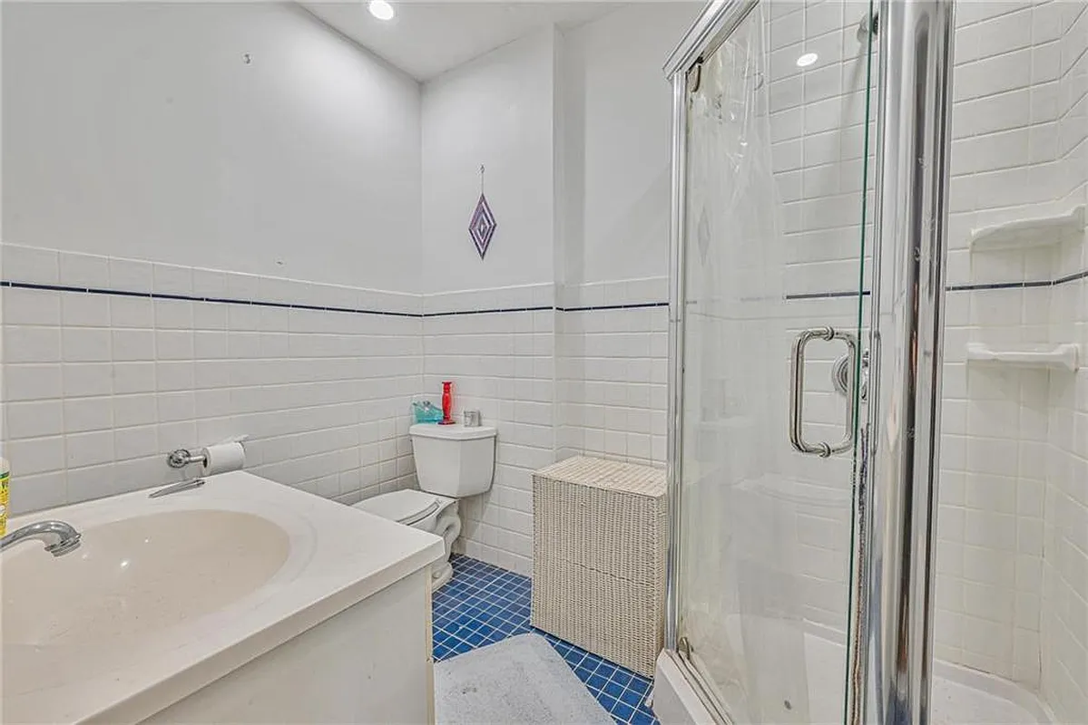 bathroom with corner shower, white wall tiles