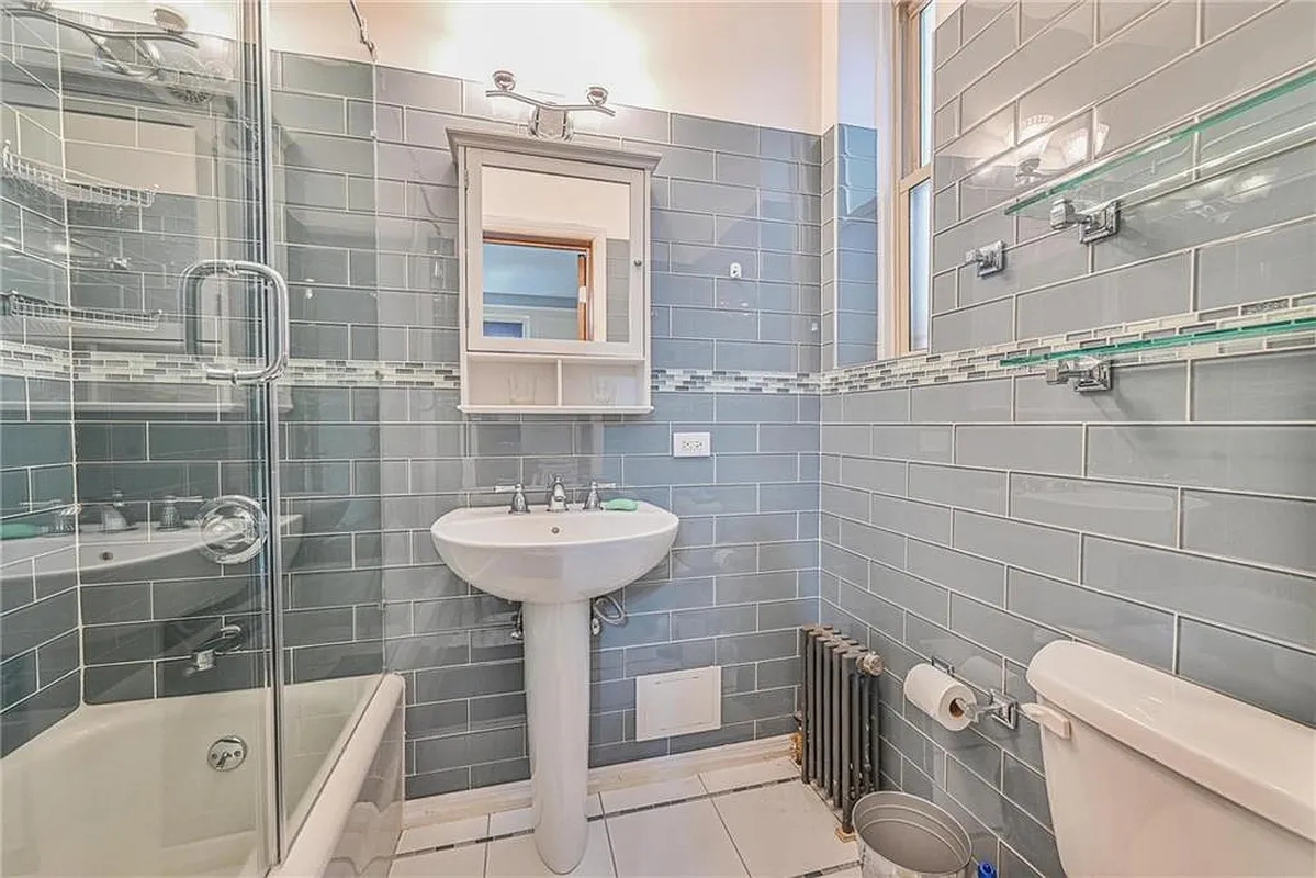 bathroom with gray wall tile, white fixtures