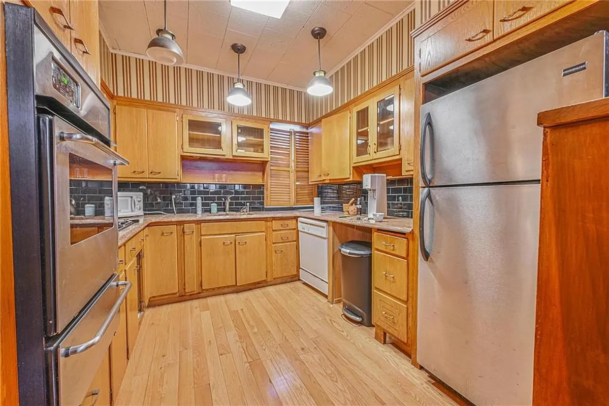 kitchen with wood cabinets, striped wallpaper, dropped ceiling tiles