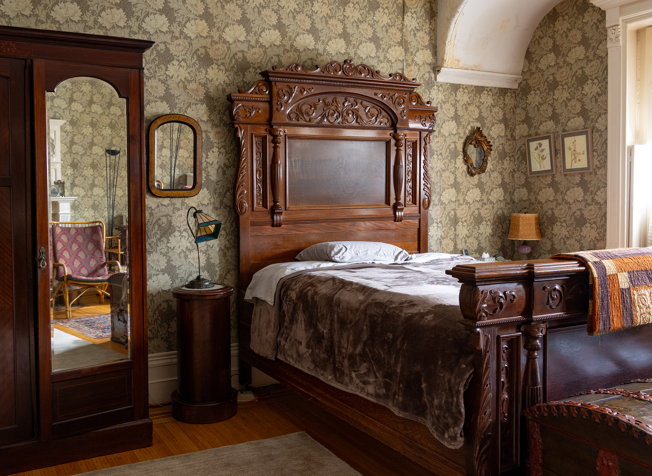 bedroom with floral wallpaper, armoire, wood floor