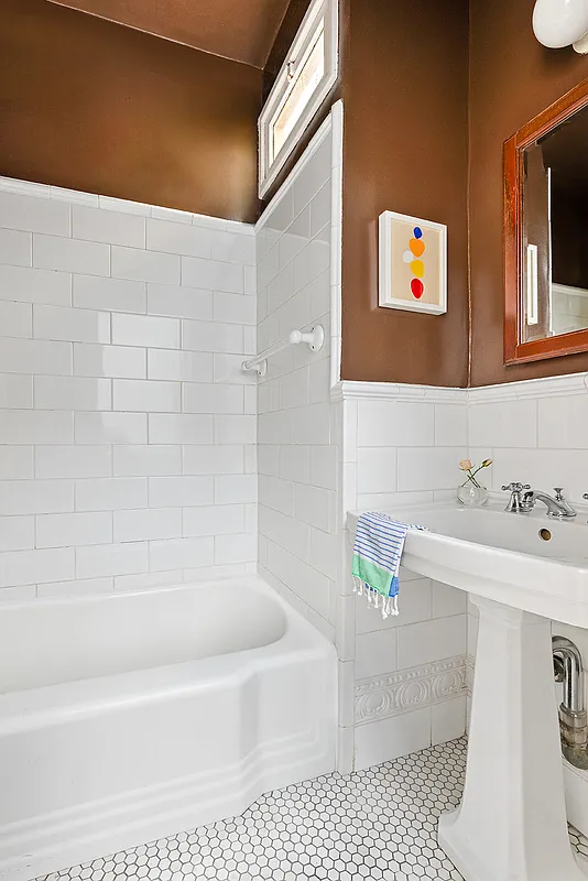 bathroom with white fixtures, white tile, and brown painted walls