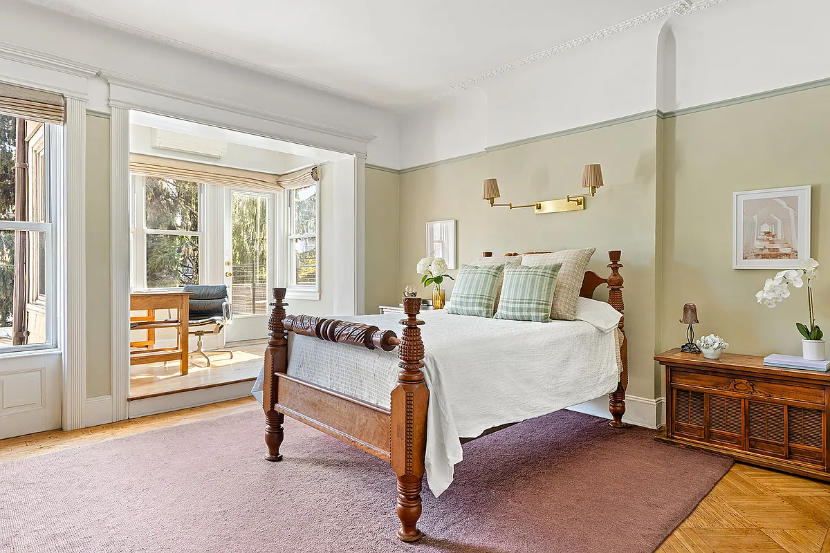 bedroom with step up to a small sunroom with access to a balcony