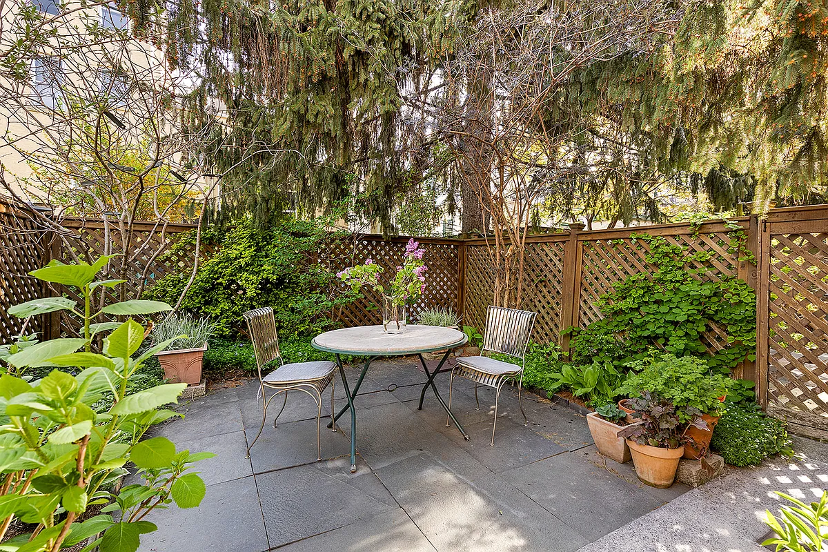 fenced in rear yard with stone patio, planting beds