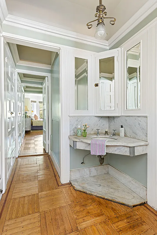 pass-through with a corner marble sink and original medicine cabinets