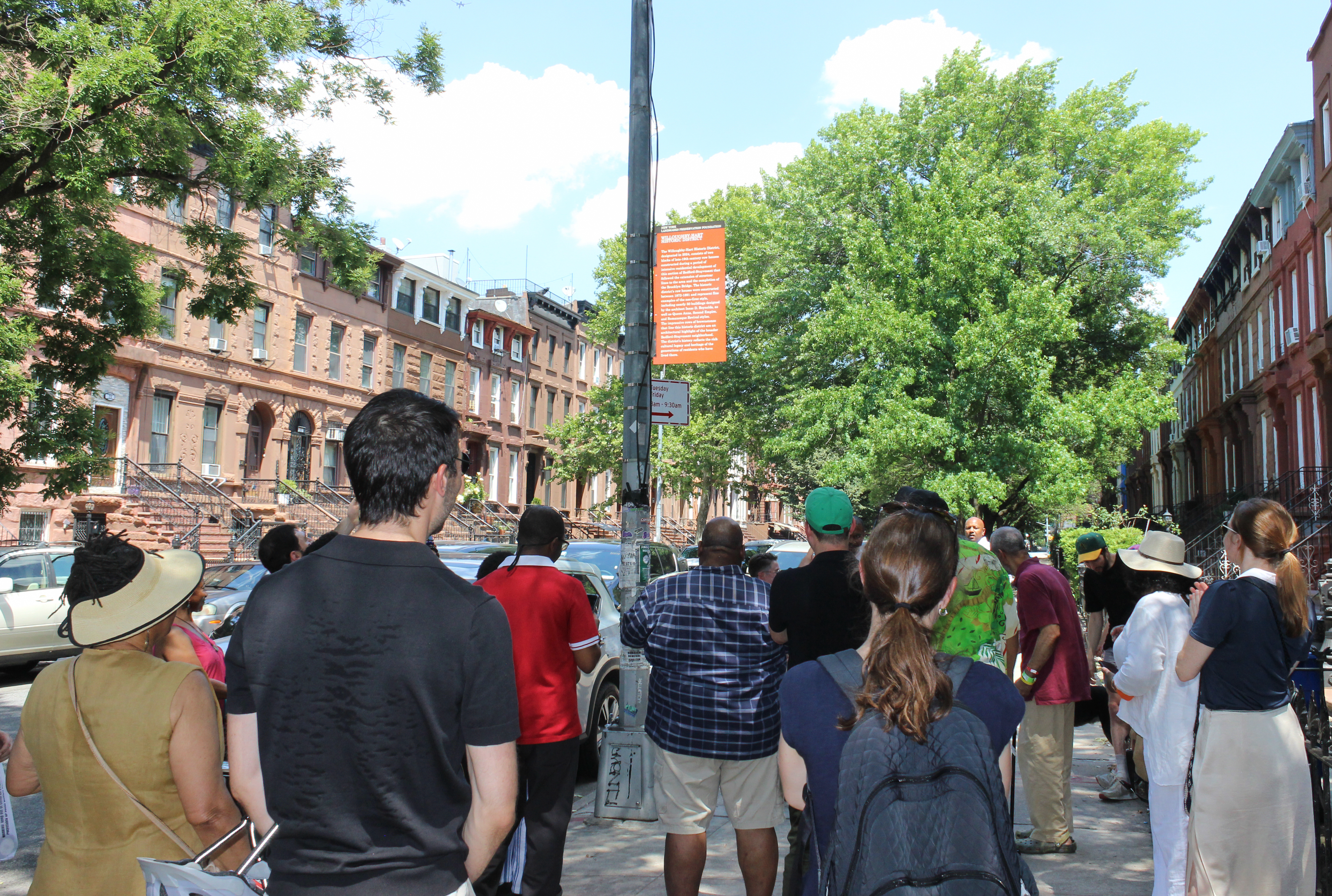 a group of people looks at the enveiled sign
