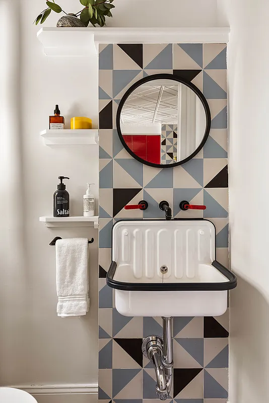 bathroom with graphic blue, white and black tile on the wall behind a wall mounted sink