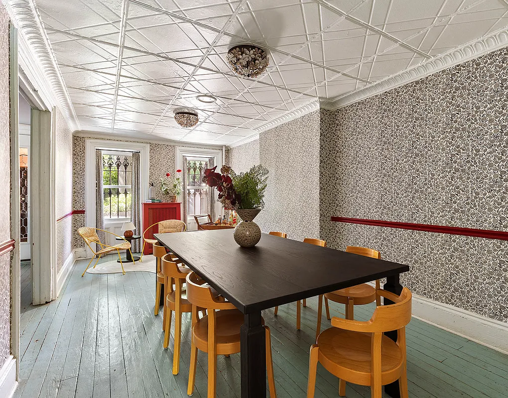 dining room with painted wood floor, floral wallpaper and a tin ceiling