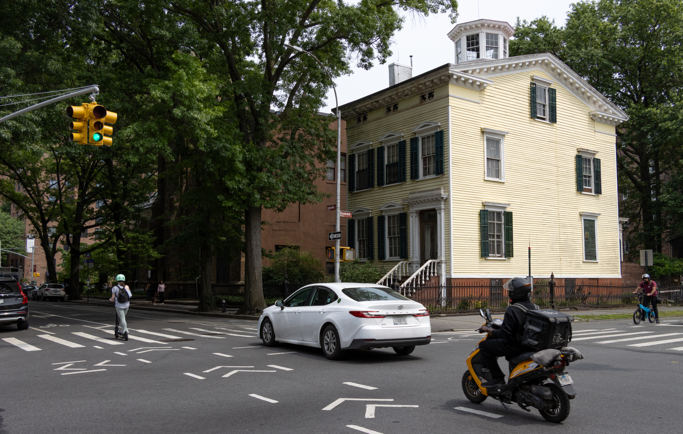 brooklyn - traffic in front of ayellow frame house on lafayette avenue