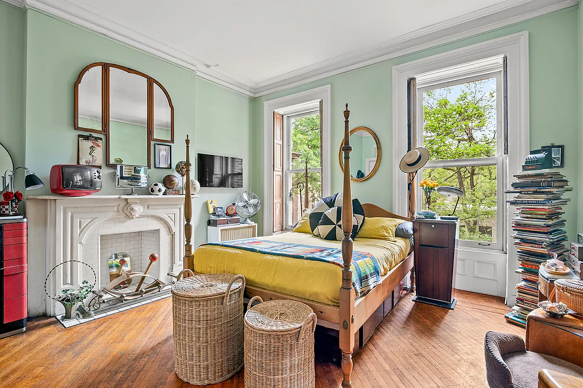 bedroom with pale green walls, wood floor, mantel