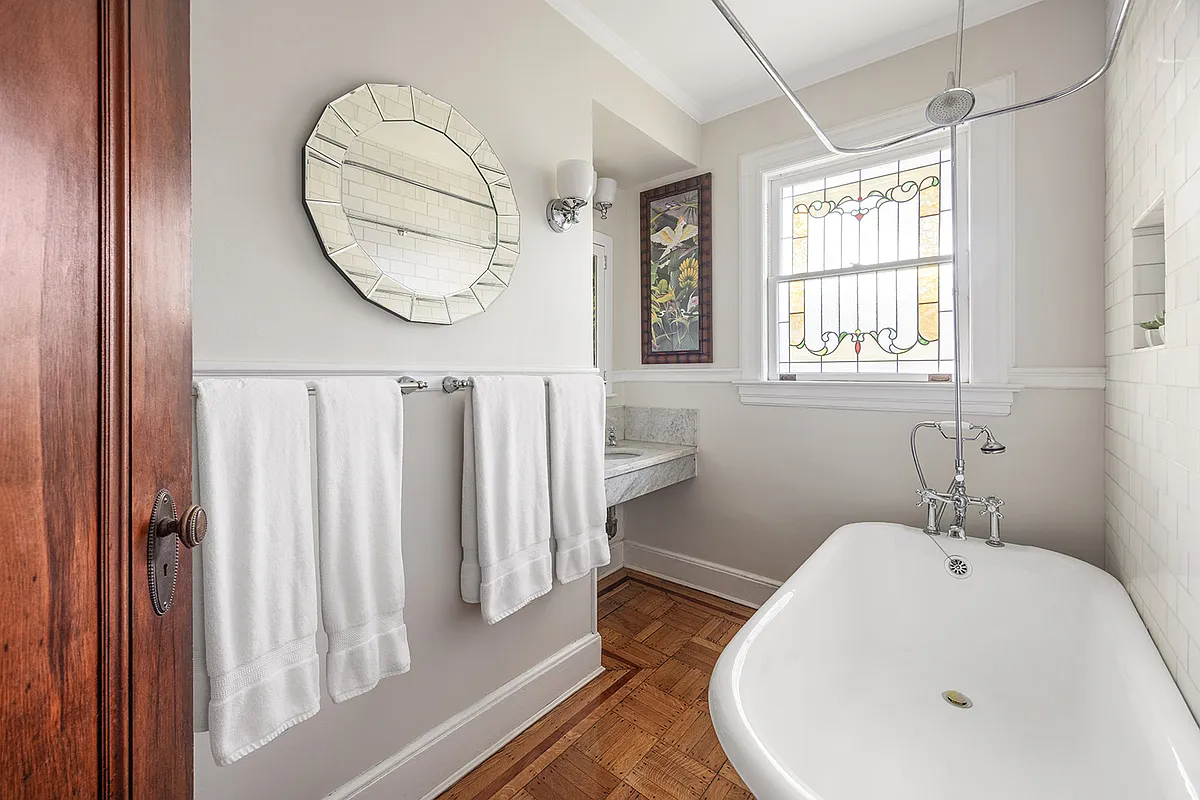 bathroom with marble sink, stained glass window, claw foot tub