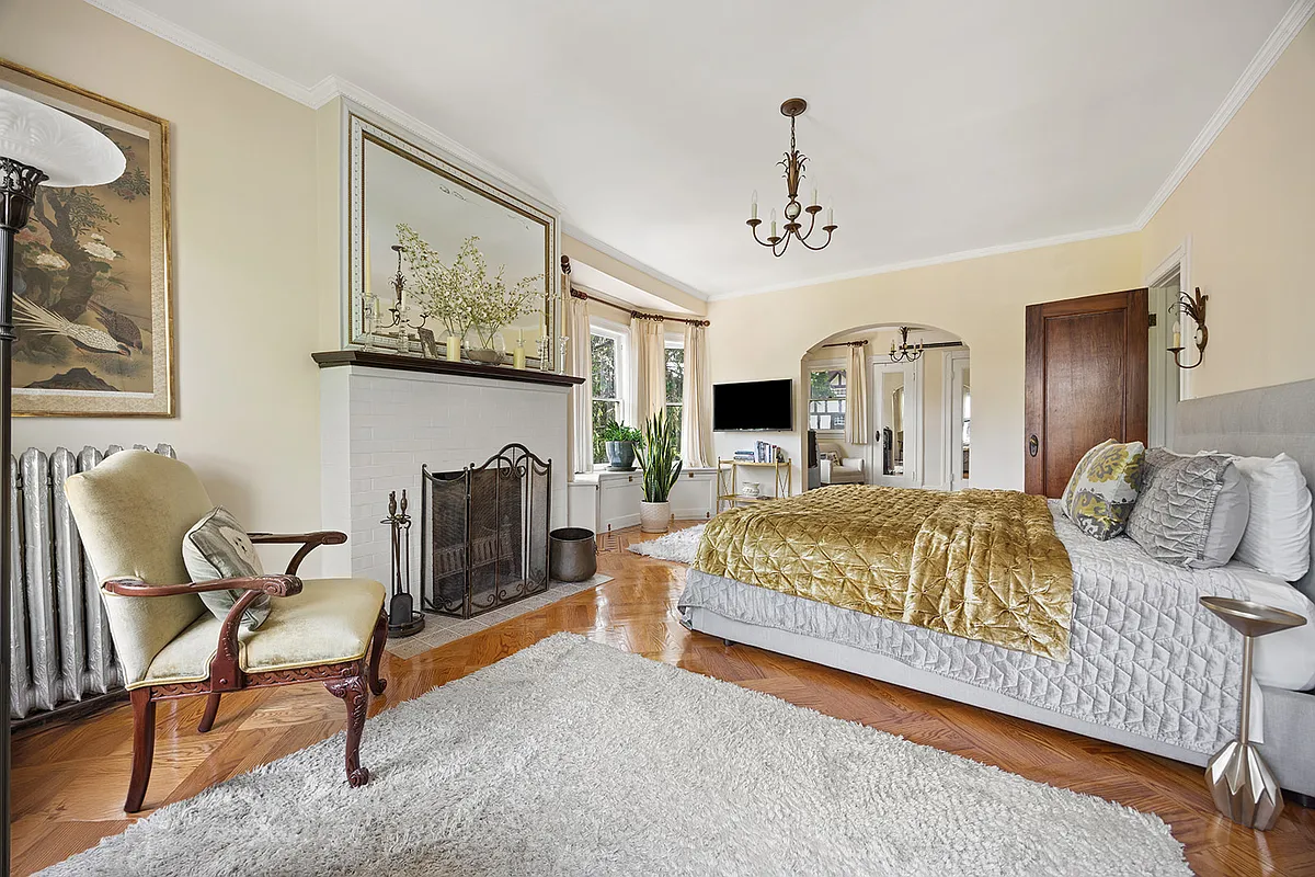 bedroom with tile-faced mantel, arched doorway to a dressing room