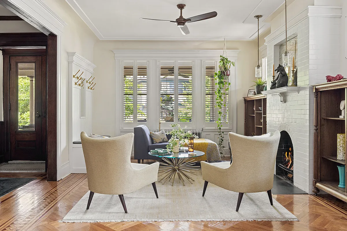living room with wood floor, windows looking out to porch, fireplace, and a ceiling fan