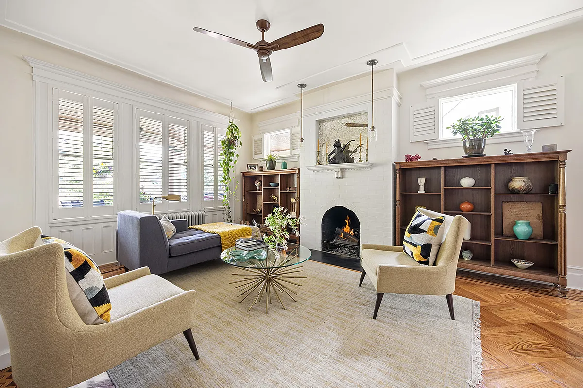 living room with wood floor, windows looking out to porch, fireplace, and a ceiling fan