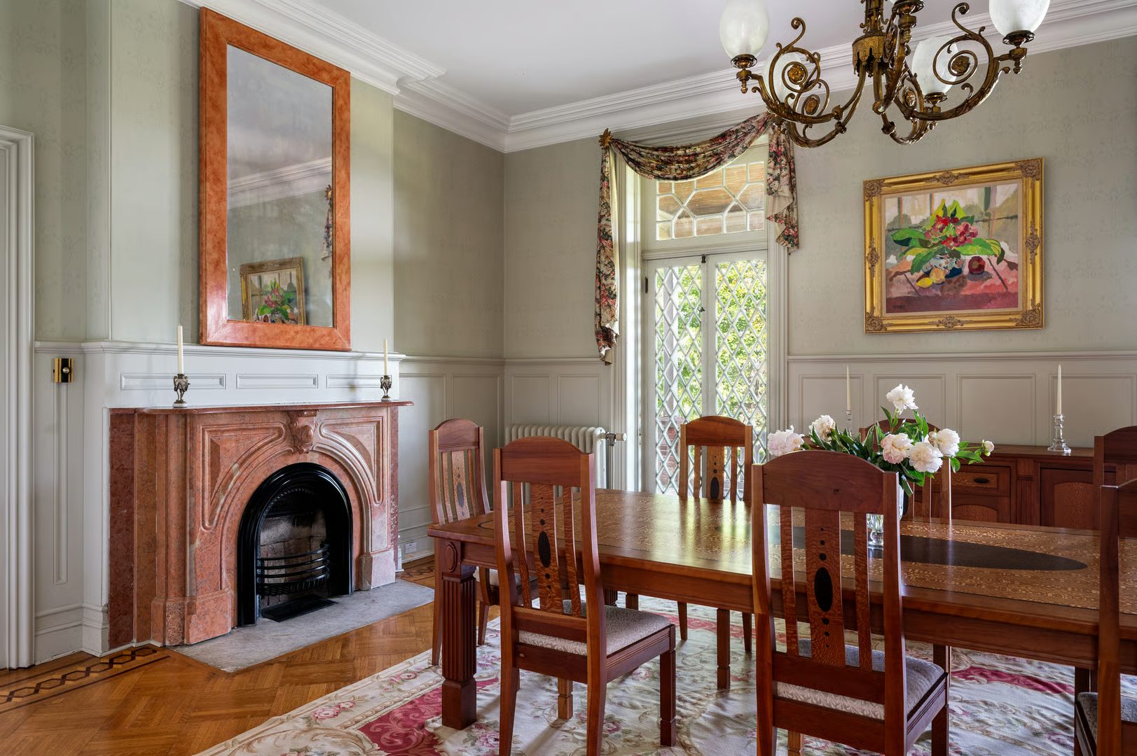 dining room with sage green walls and wainscoting and a marble mantel
