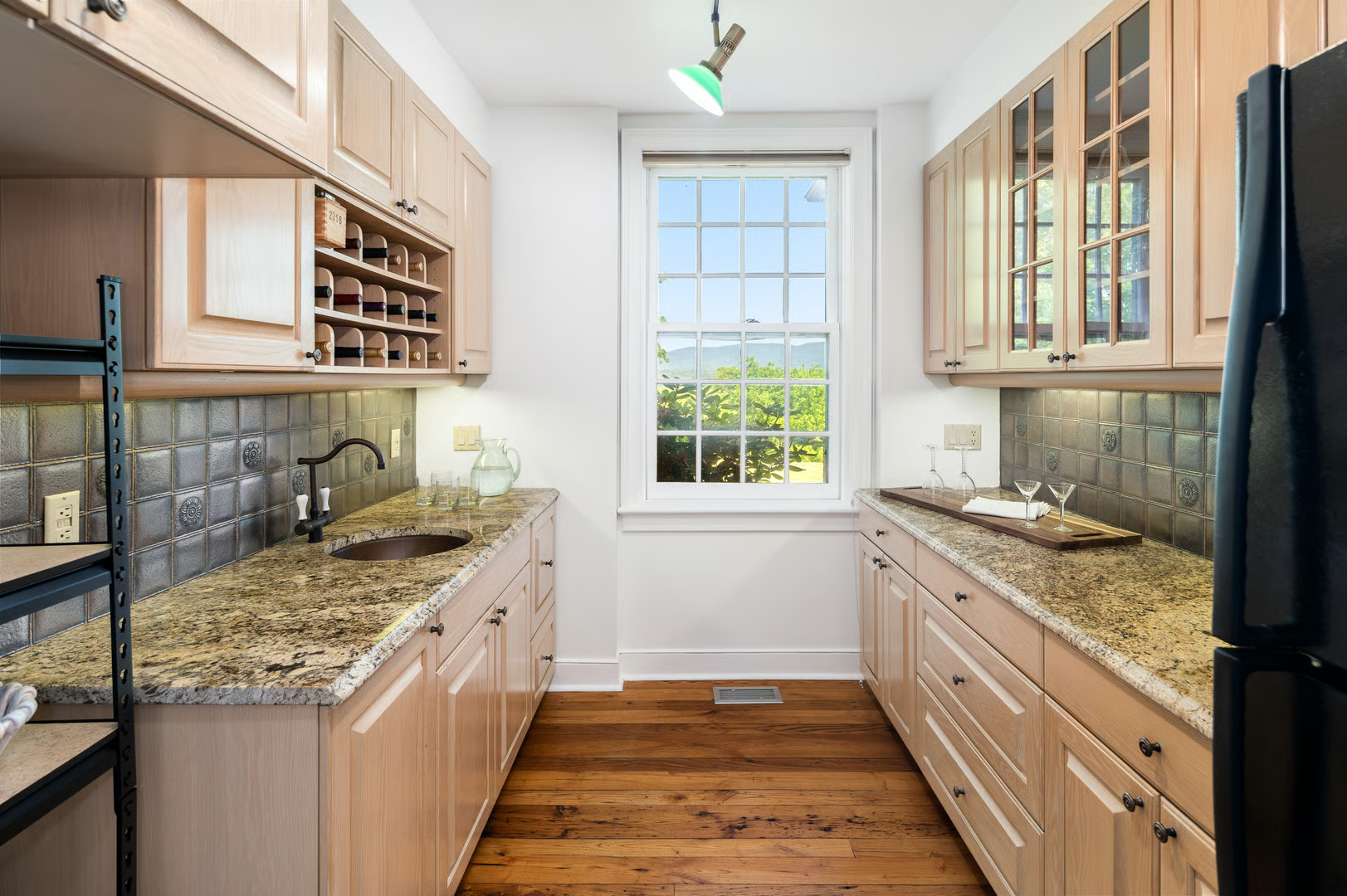 windowed butlers pantry with pale wood cabinets, granite