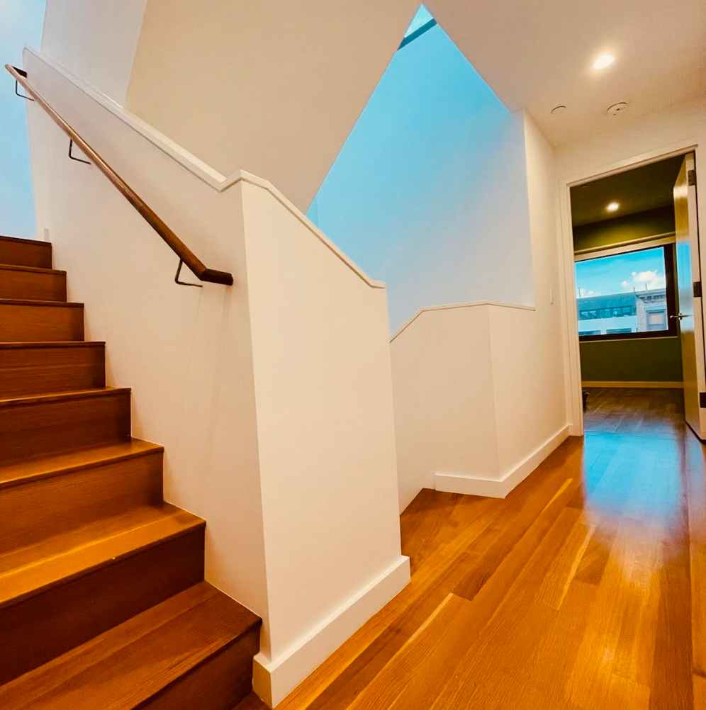 stair and hallway with white walls and wood floors