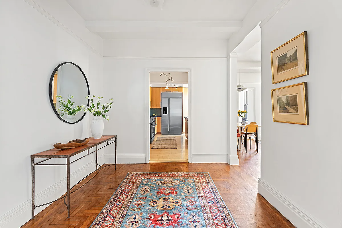 foyer with wood floor, view into the kitchen and the den