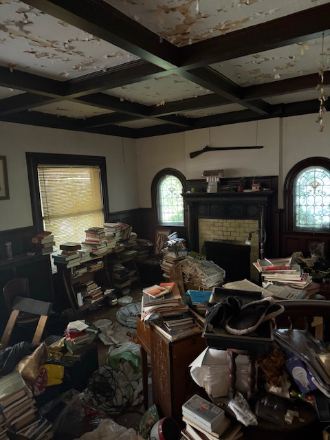 room with beamed ceiling, peeling paint, stained glass, mantel, and lots of stuff
