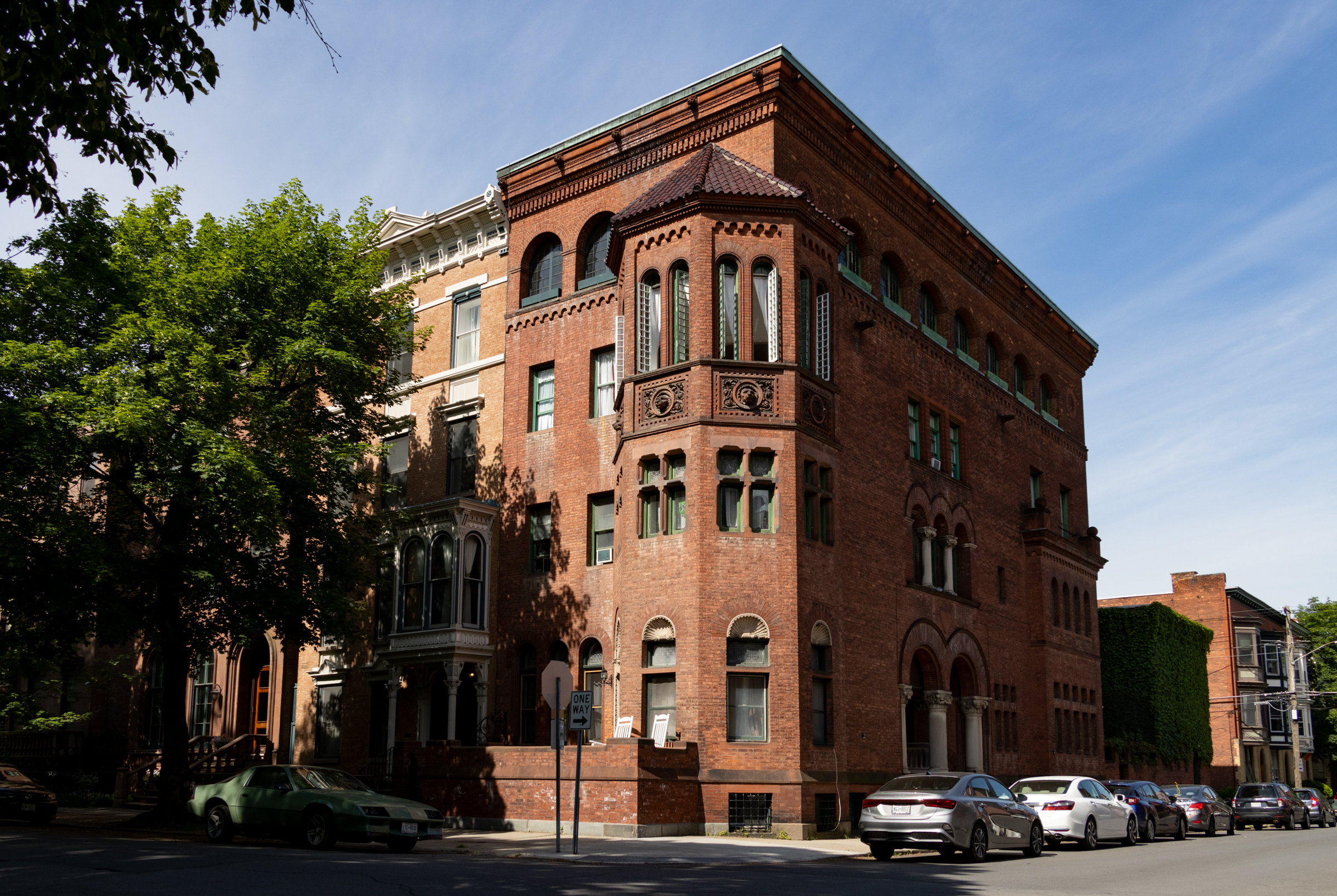 brick corner house with arched windows and a tile roof on a full height bay