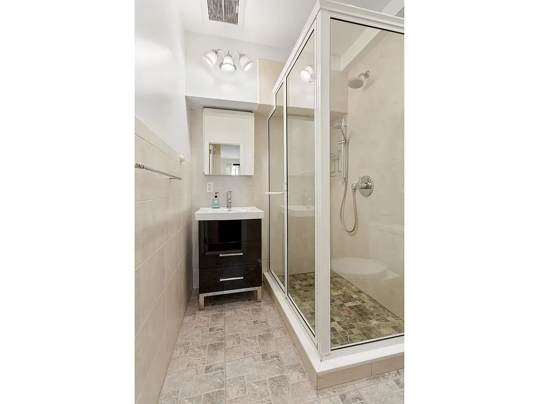 bathroom with beige tile and a glass doored shower