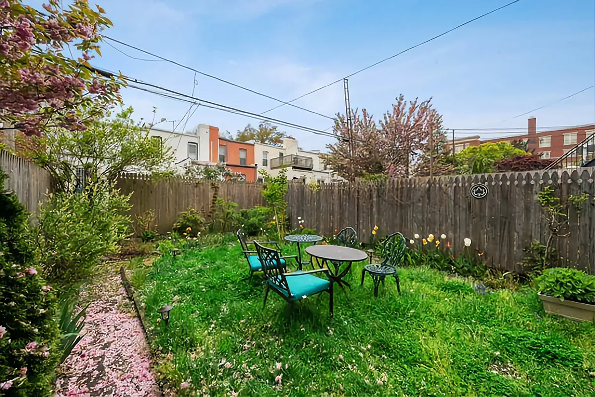fenced-in rear yard with a lawn in the center and planting beds around the edges