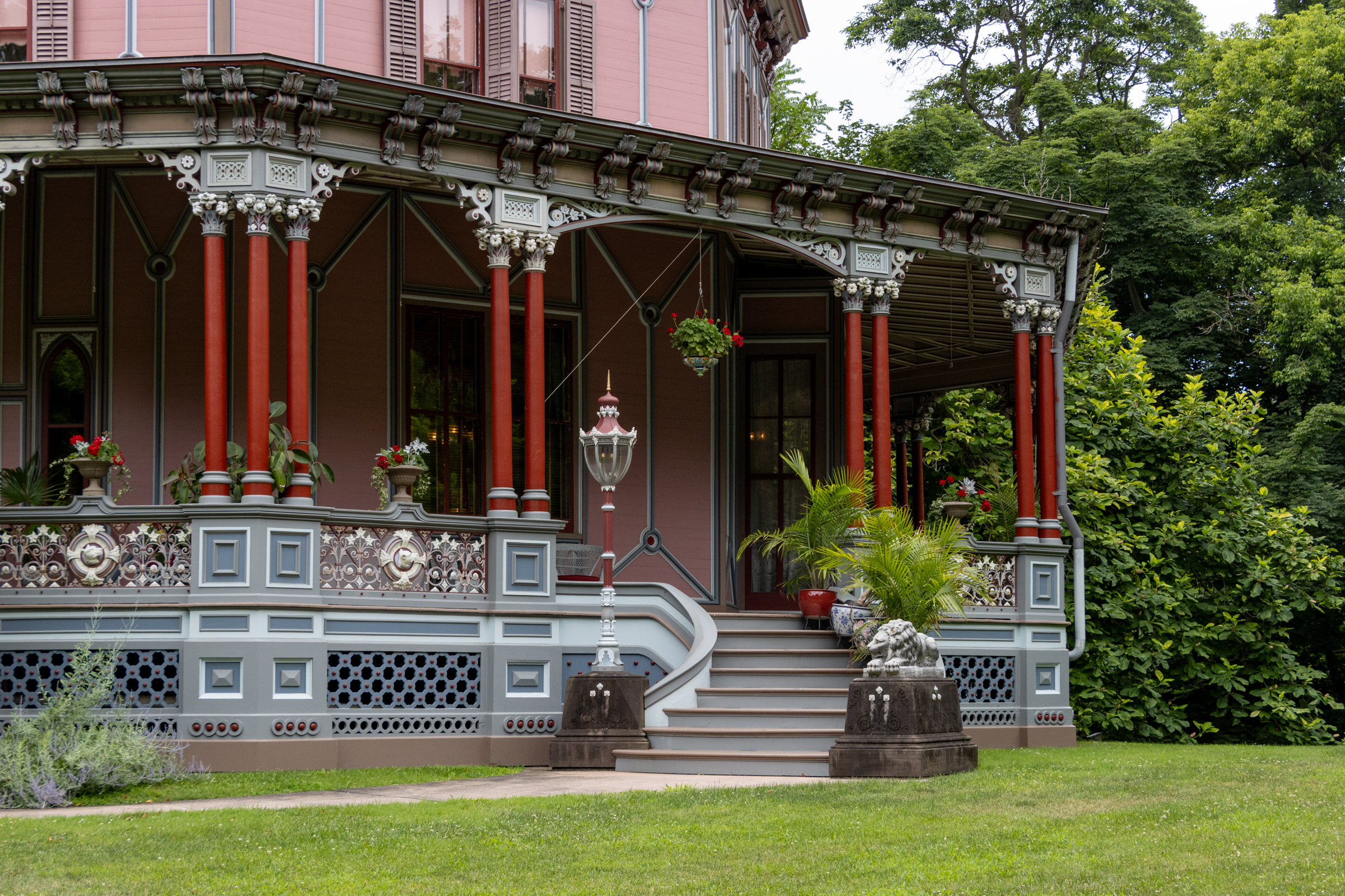 colorful porch of a pink house with a curved stair lined with planted palms