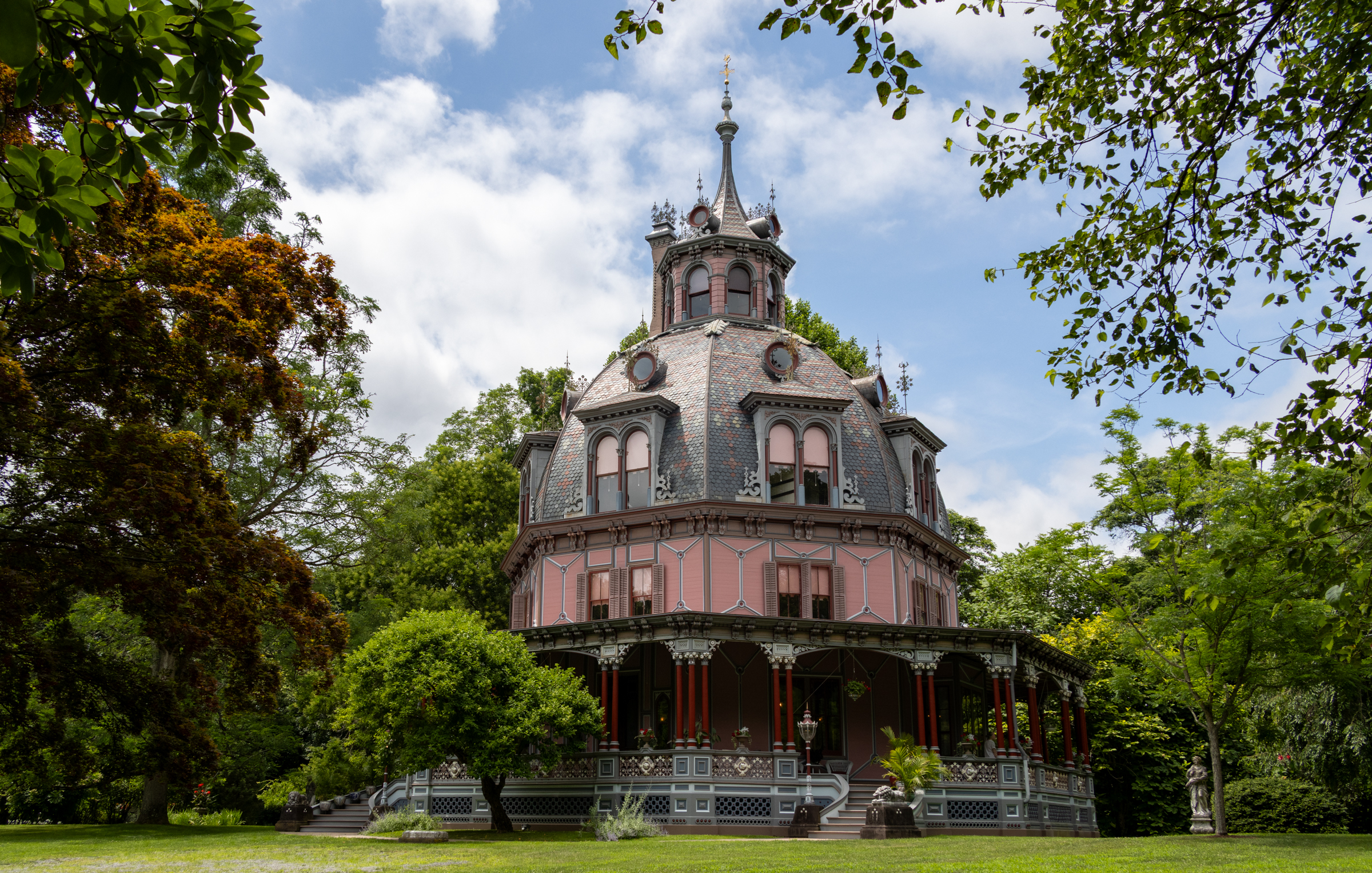 a pink octagon house with a porch, a dome, and a cupola