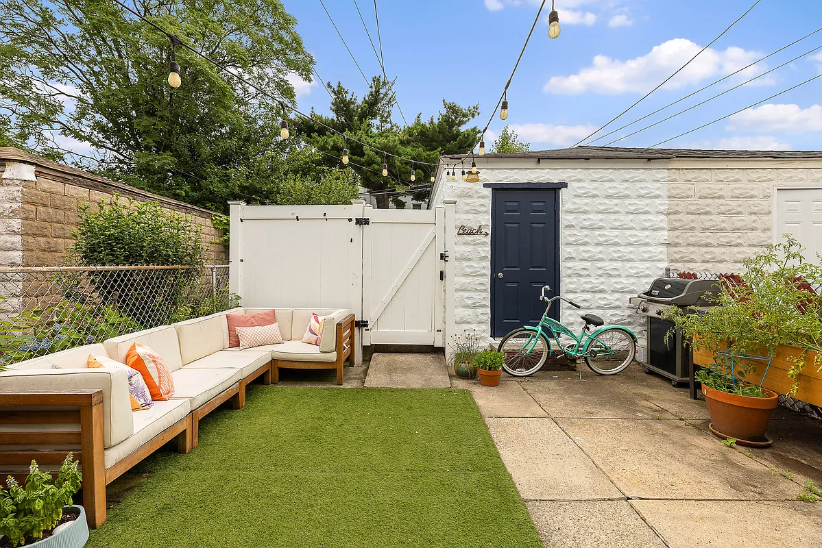 rear yard with artificial grass carpet over a section of concrete and a view to the garage