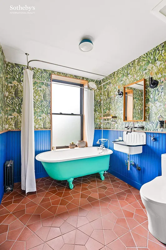 bathroom with a terra cotta tile floor, blue wainscoting, and a claw foot tub painted green