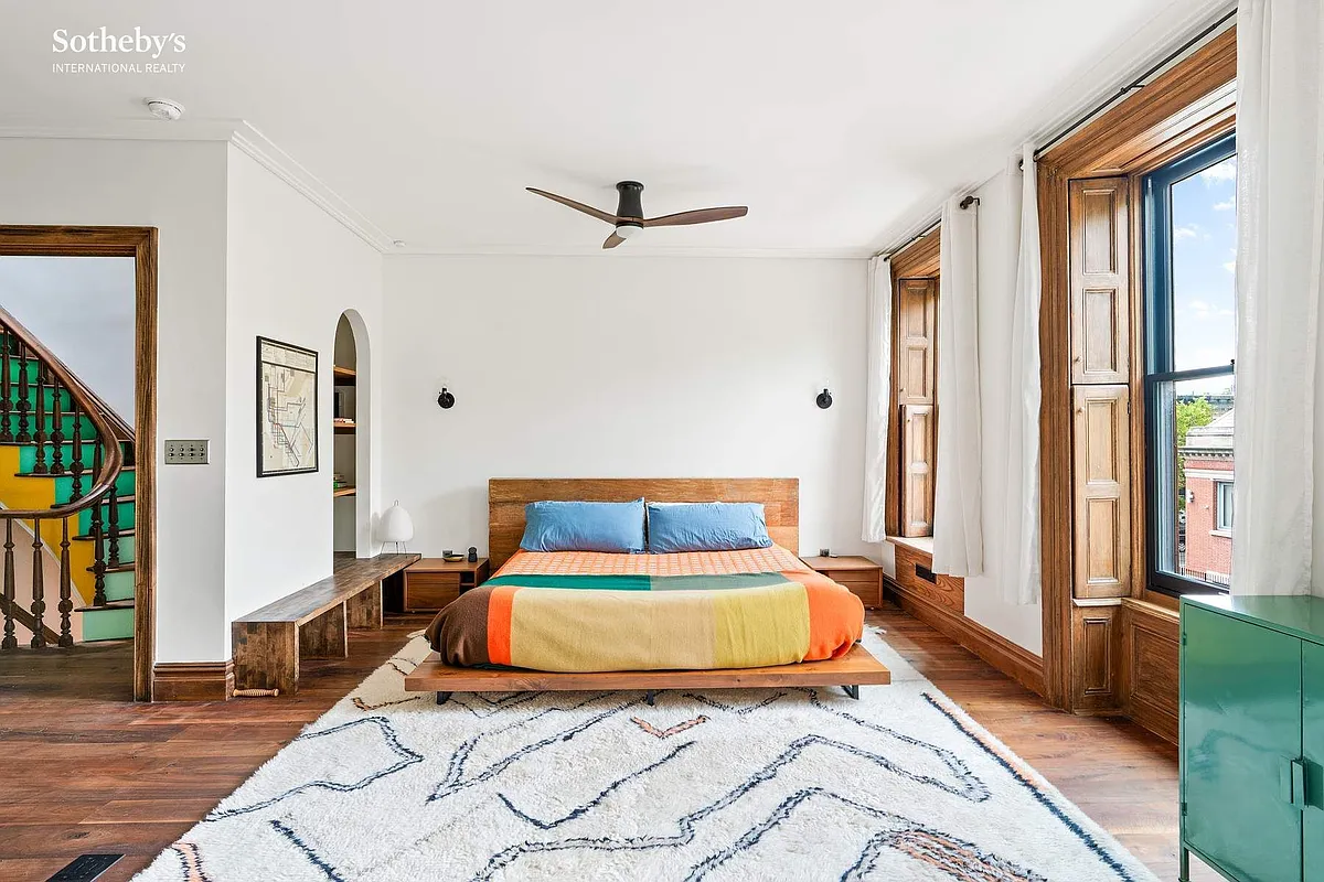 bedroom with wood floor, original interior shutters, a ceiling fan