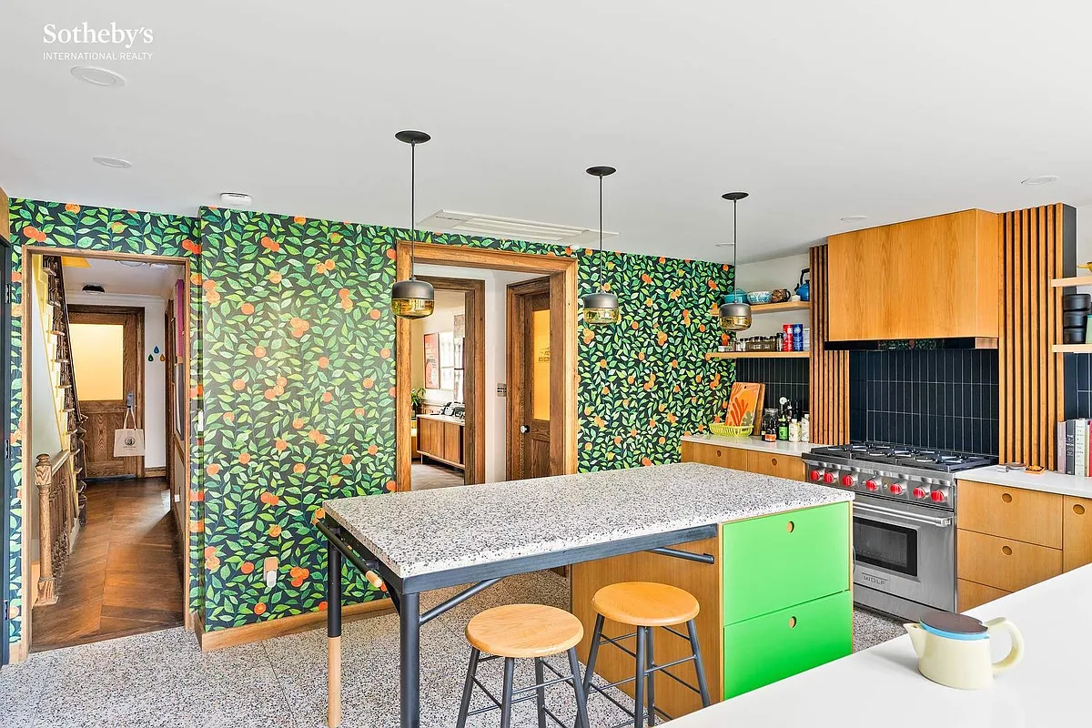 kitchen with leafy wallpaper with oranges, wood cabinets and an island with green drawers