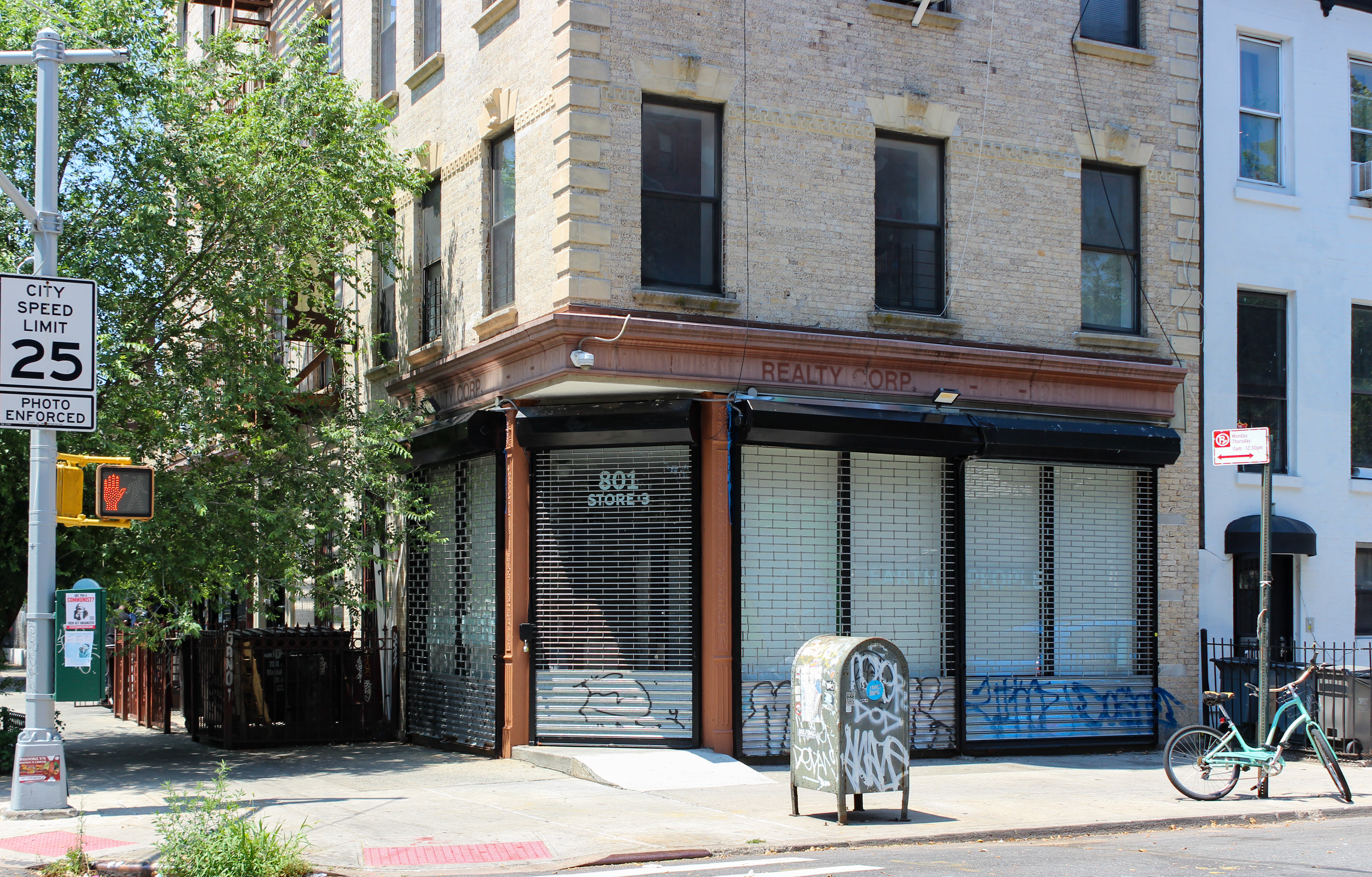 a corner storefront with gates and papered over windows