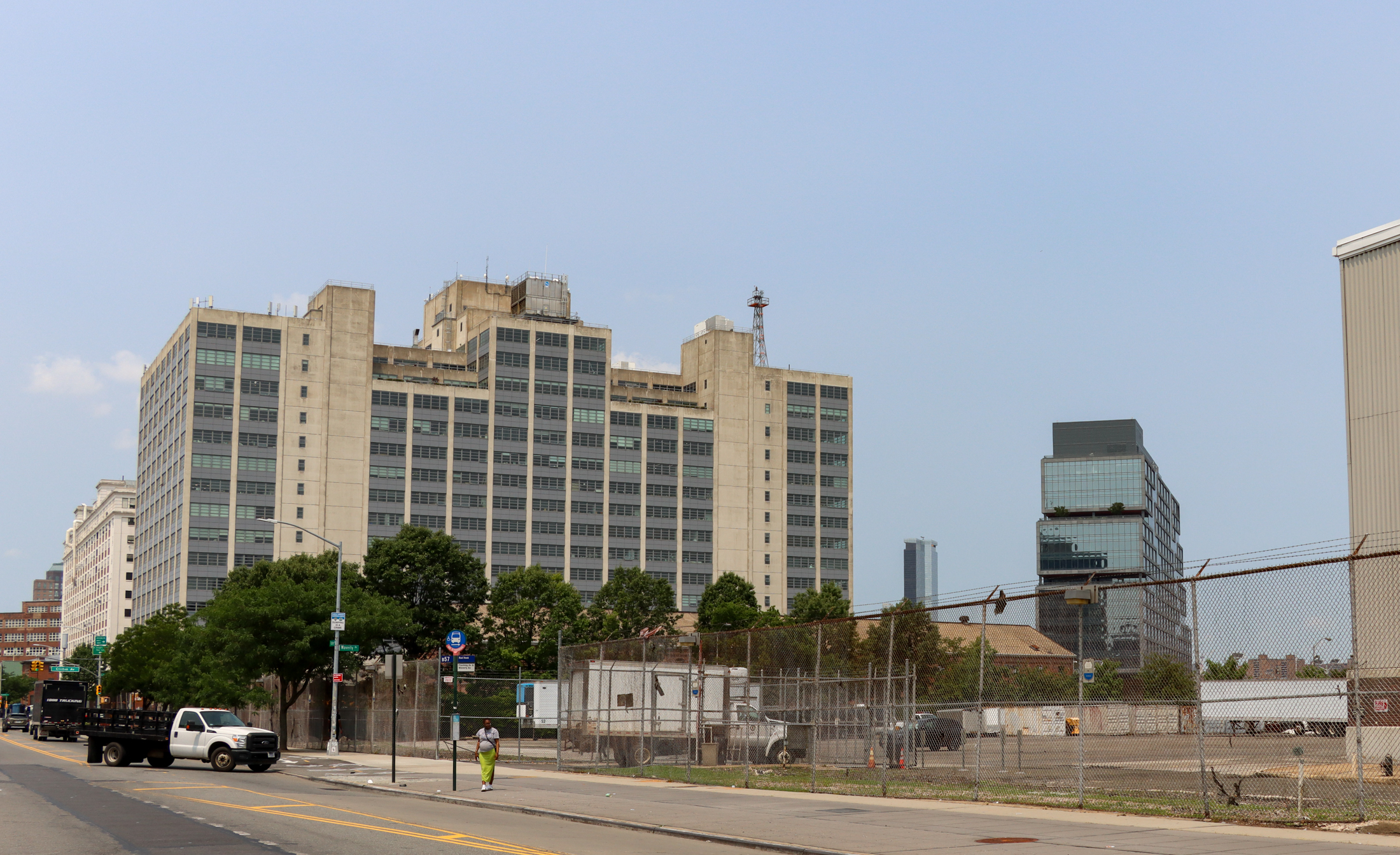 view on flushing avenue with large buildings of the navy yard seen behind a chain link fence