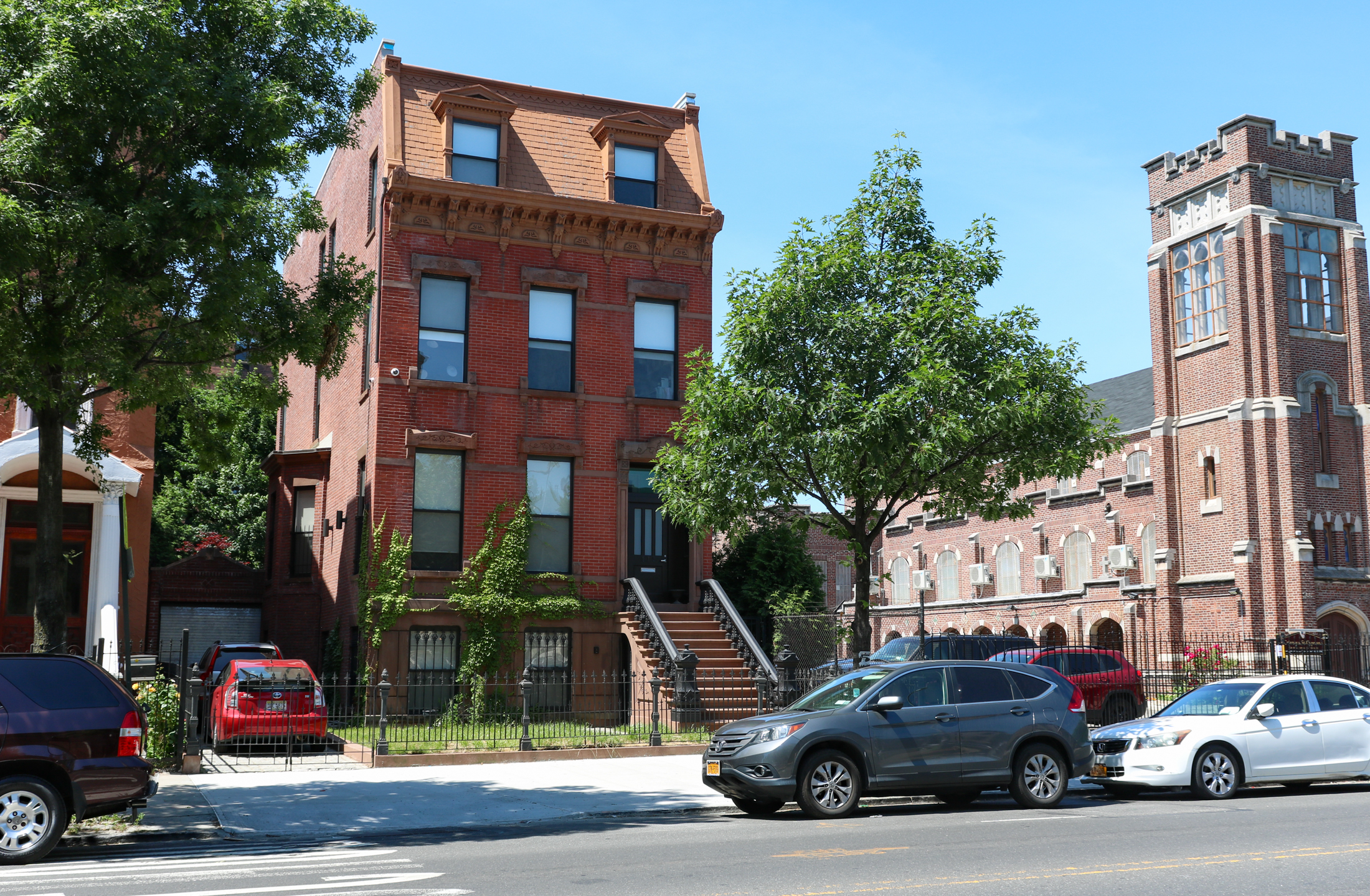 a parking lot between a brick church and a brick house