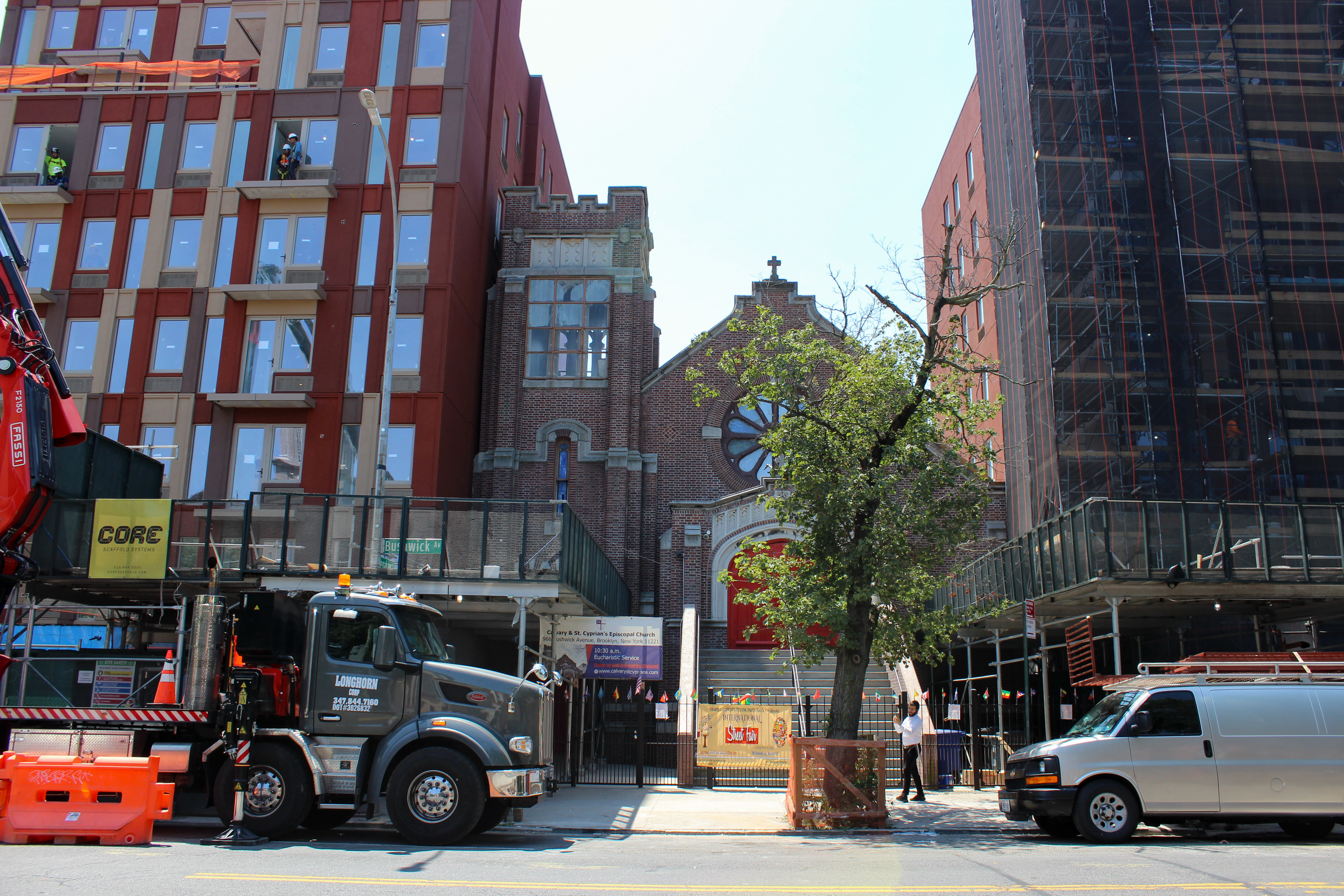 a brick church with buildings under construction on either side