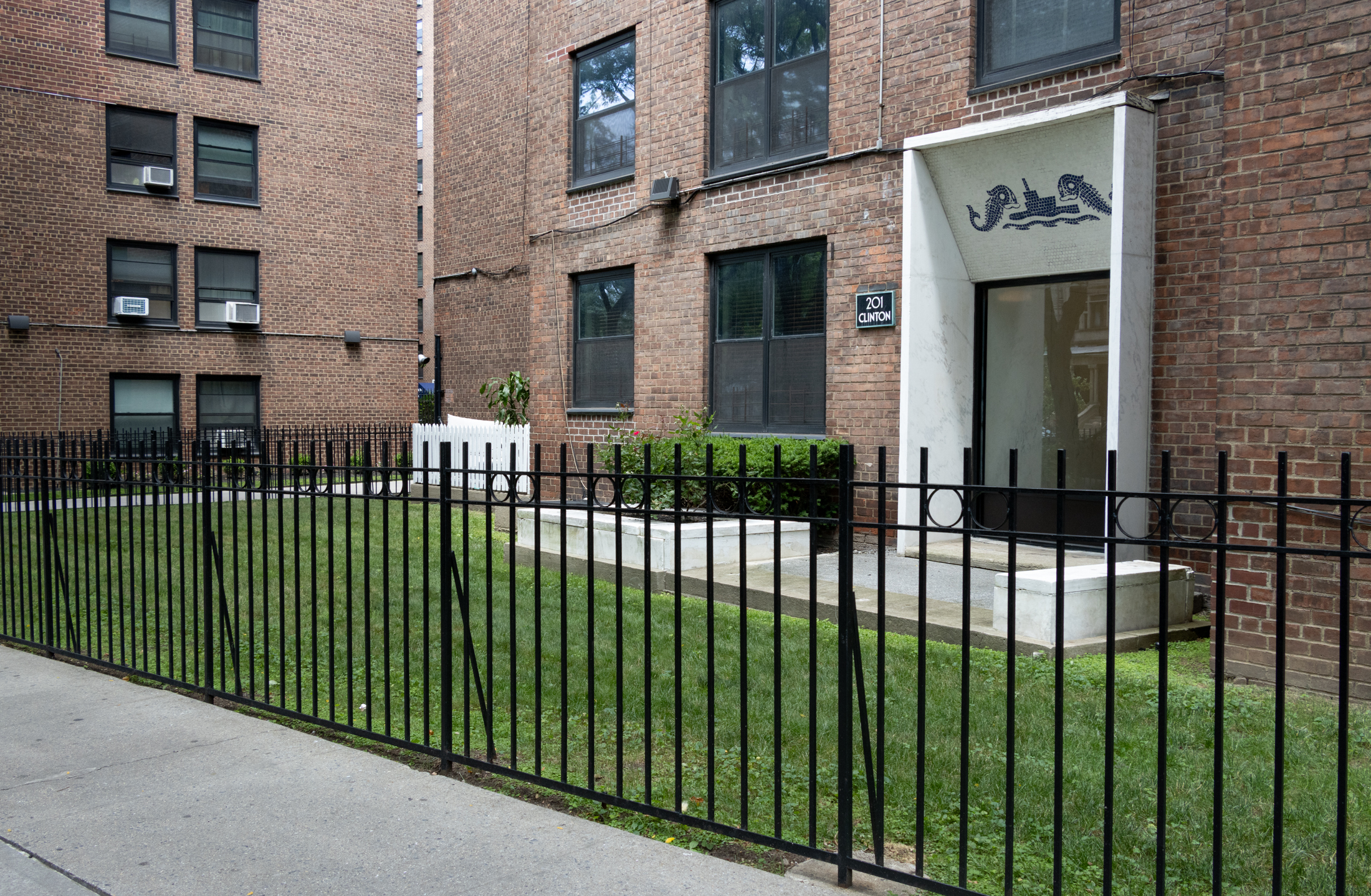 iron fence and a bit of lawn in front of a door with a blue and white mosaic above