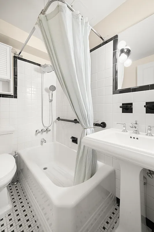 bathroom with white fixtures and black and white floor tile
