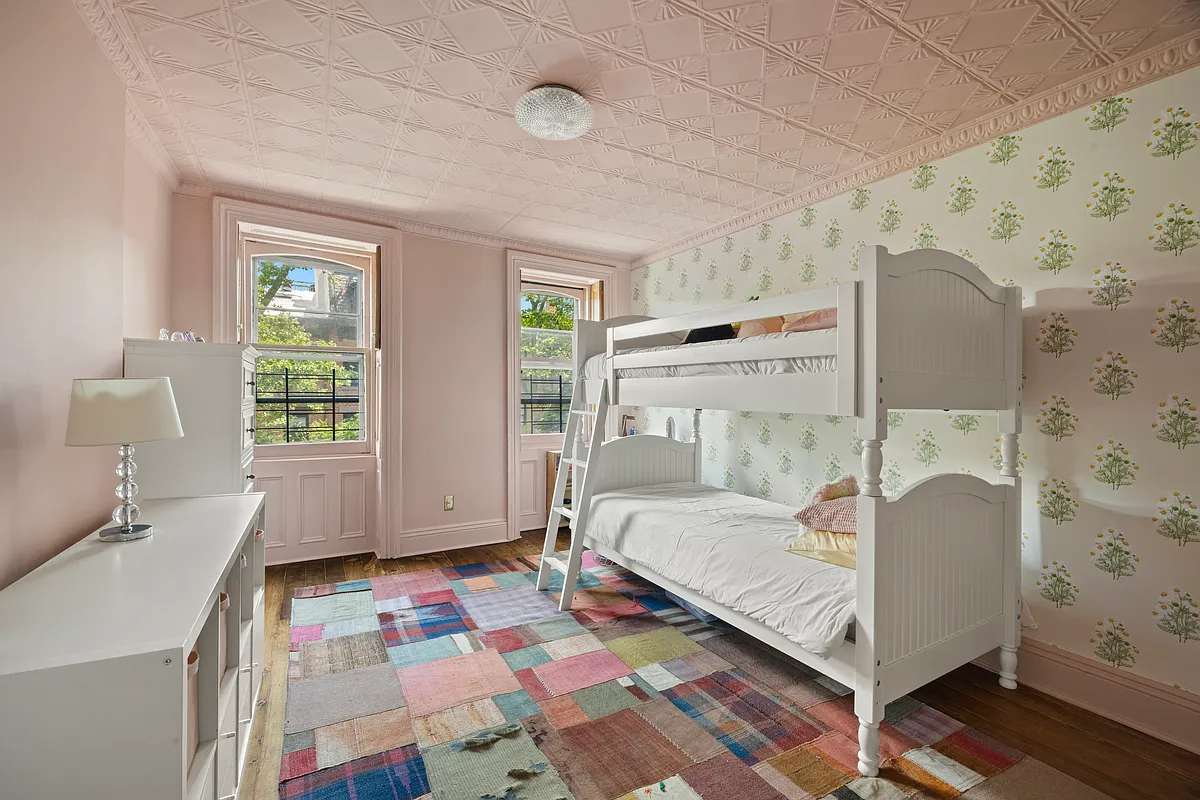 a bedroom with pink walls, floral wallpaper and a tin ceiling painted pink