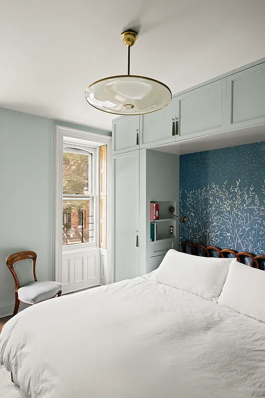 bedroom with built-in storage surrounding the bed and blue wallpaper behind the headboard