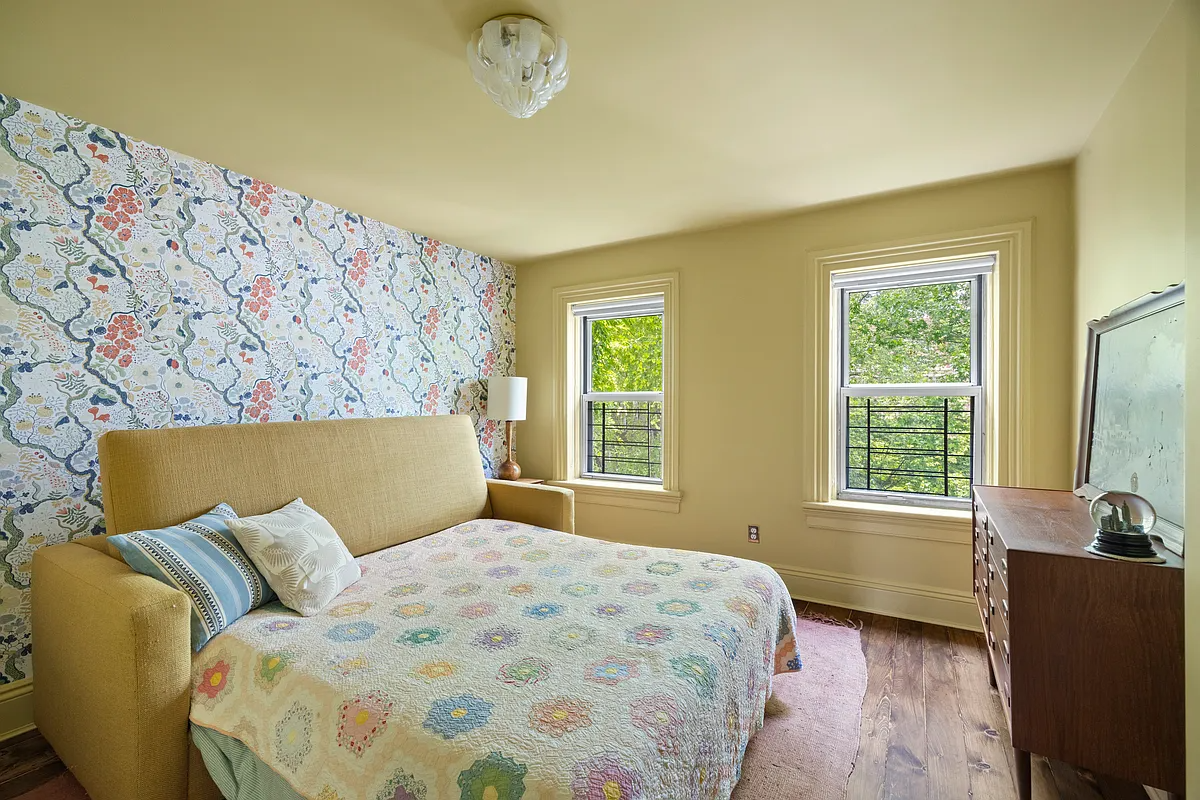 a bedroom with one wall with floral wallpaper and other walls and ceiling painted yellow