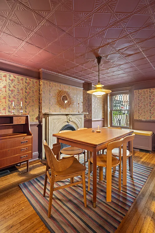 a dining room with floral wallpaper and a tin ceiling painted dark rose