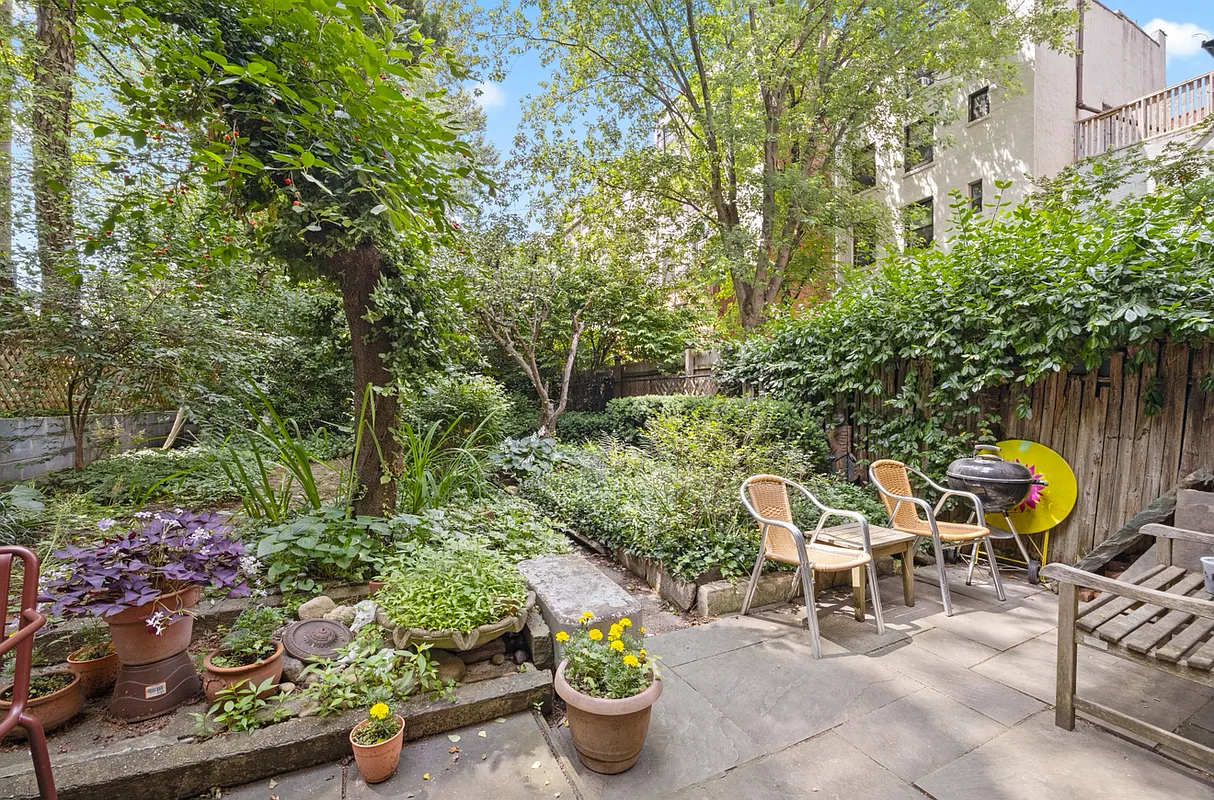 rear yard with raised beds and a paved seating area