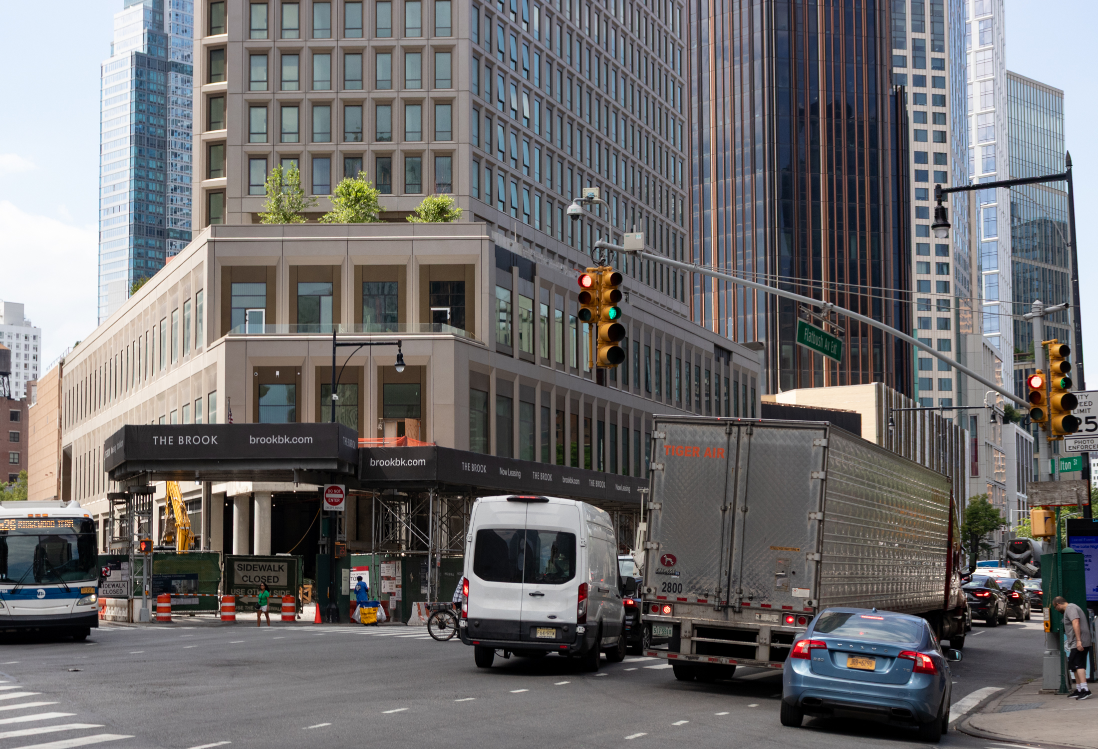 traffic on the corner with view of construction fence still around base of the building