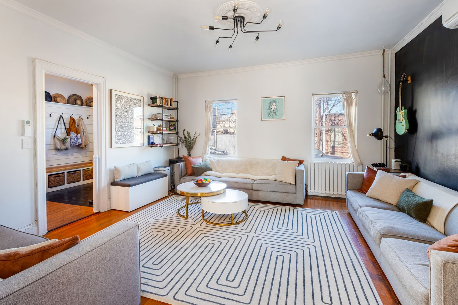 living room with wood floor, two windows, and one blue wall