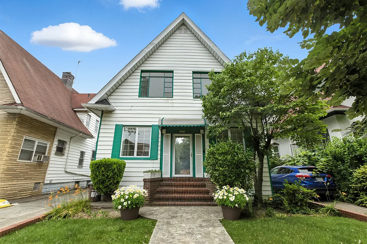 exterior of a detached house with white siding and green shutters