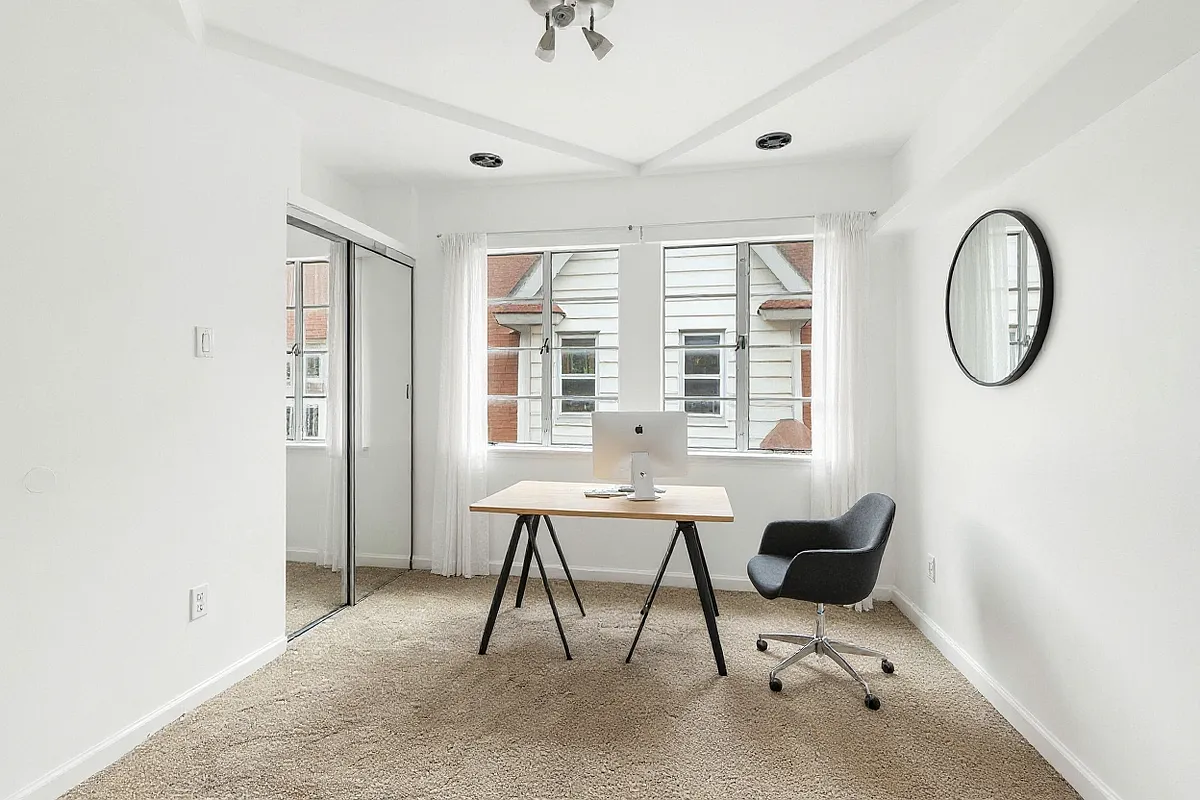 a virtually staged bedroom with carpet, mirrored closet doors, and a desk