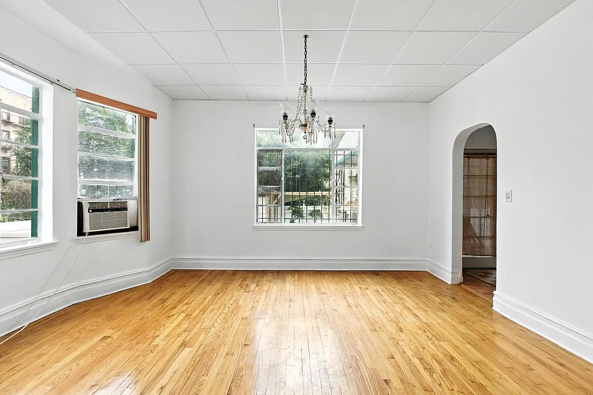 a dining room with white walls, a wood floor, a drop ceiling, and two exposures
