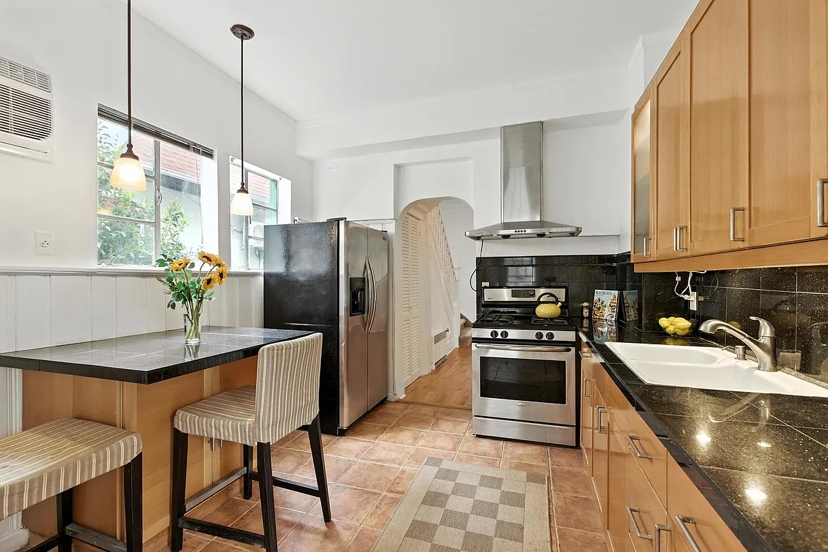 a kitchen with beige floor tile, brown cabinets, and a black countertop